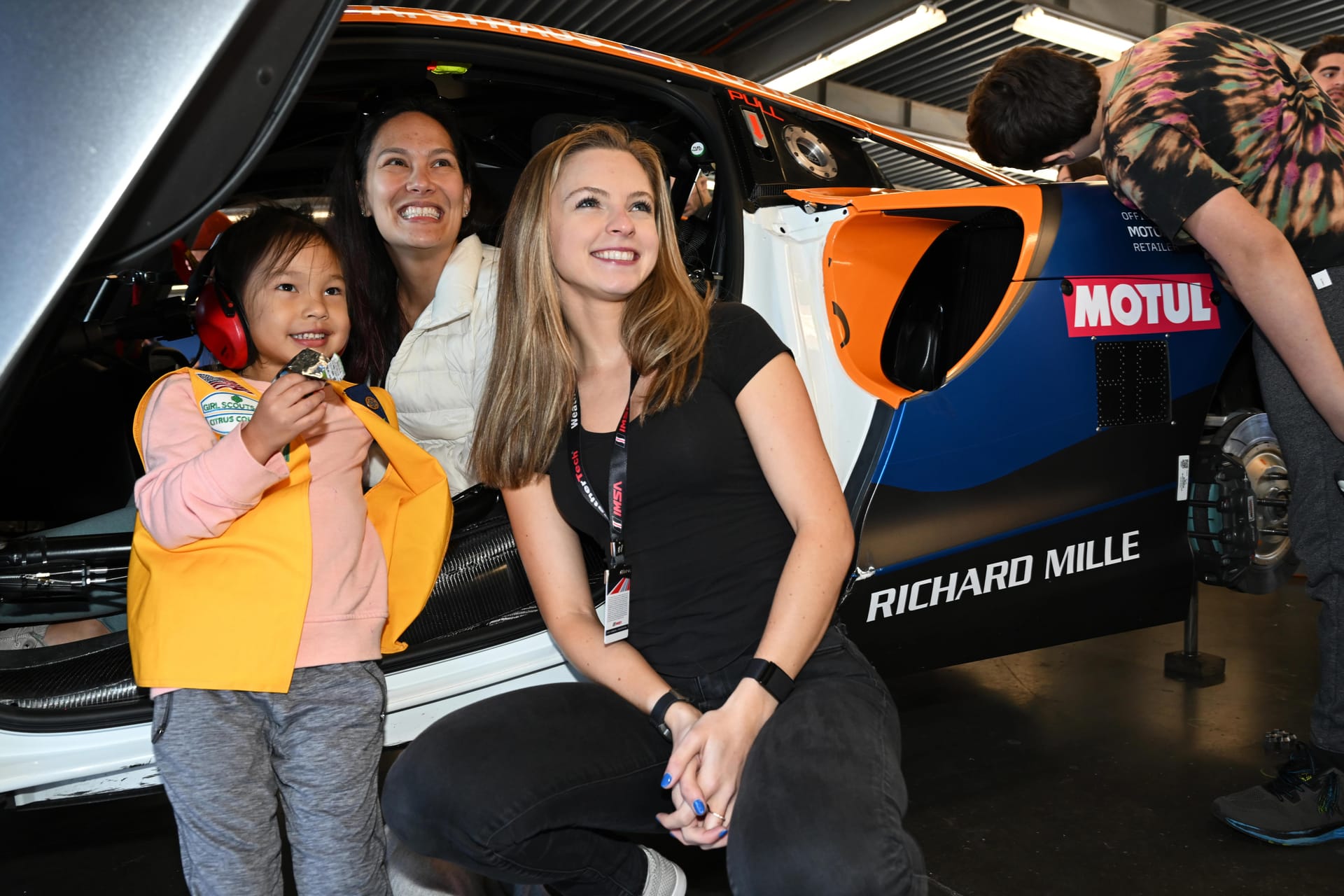 Aurora Straus poses with fans in front of racecar