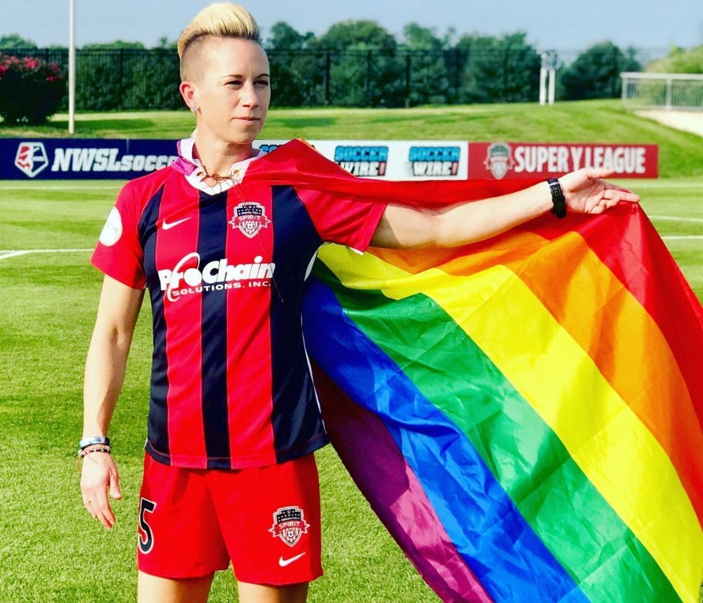 Joanna Lohman wears rainbow pride flag like a cape on soccer field