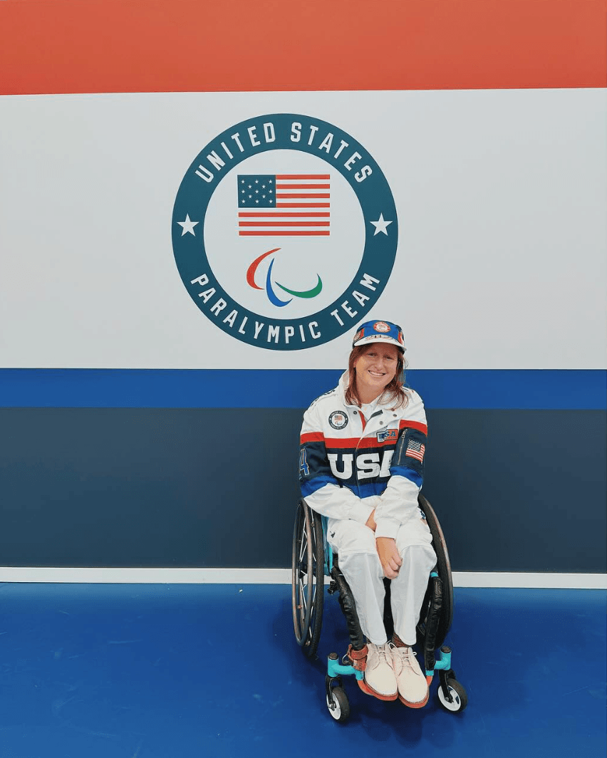 Courtney Ryan smiles in front of US Paralympic Team logo