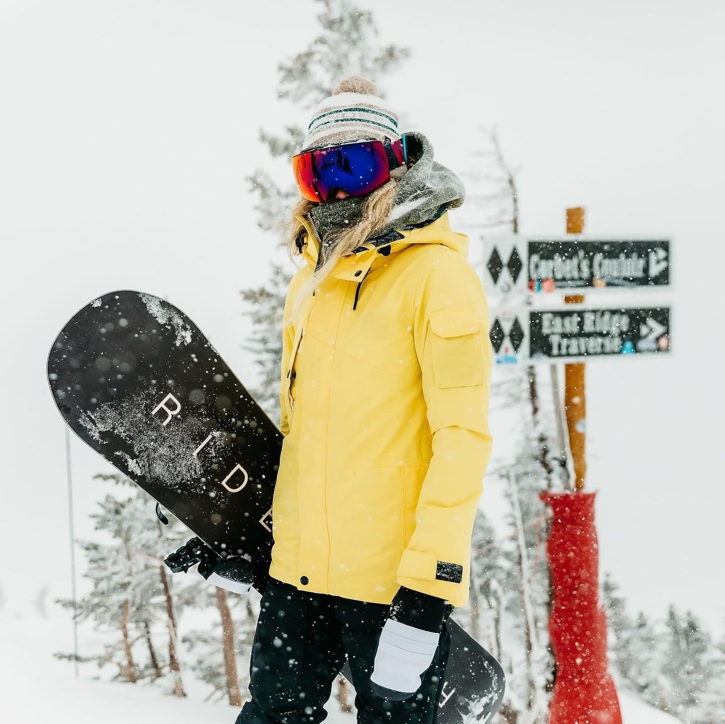 Jessika Jenson holds a snowboard atop of snowy ski slope