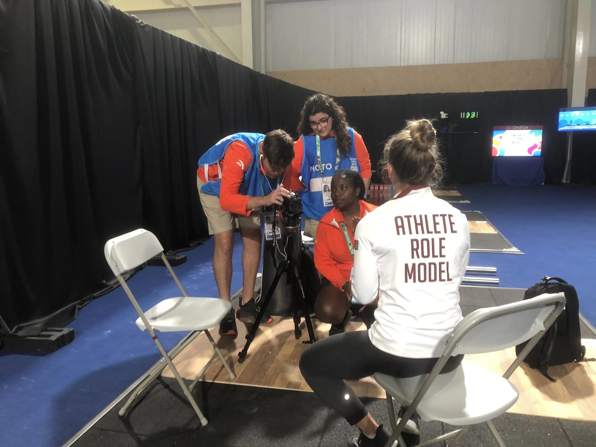 Morghan sits on a chair being filmed wearing a shirt that reads "athlete role model"