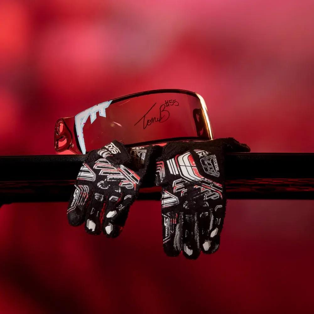 Photo of autographed riding gloves and visor in front of red background