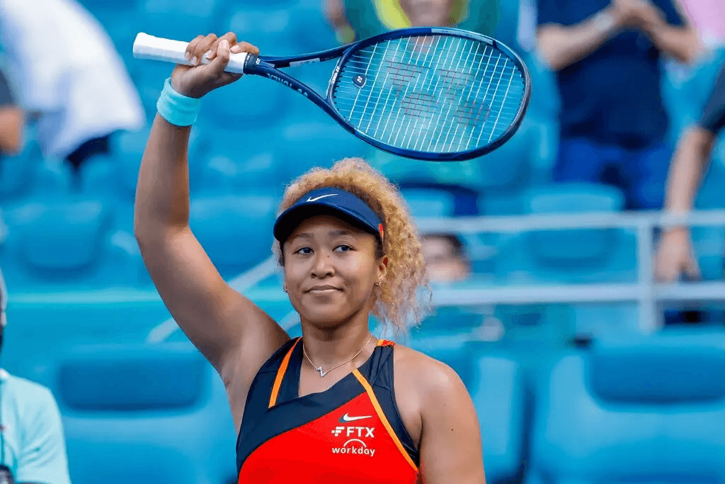 Naomi Osaka waving tennis racket at a tournament