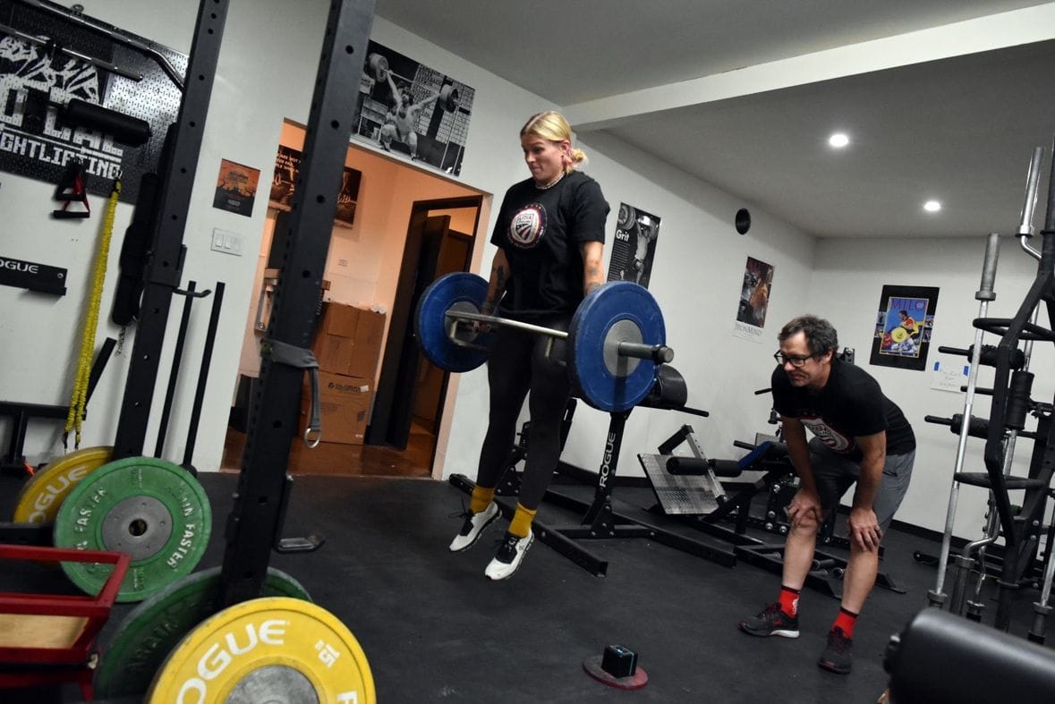 Mallory lifting weights with a trainer