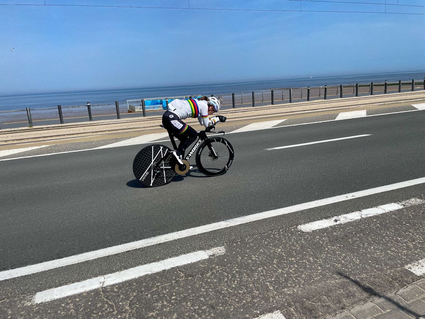 Samantha cycling competitively on a beachside road