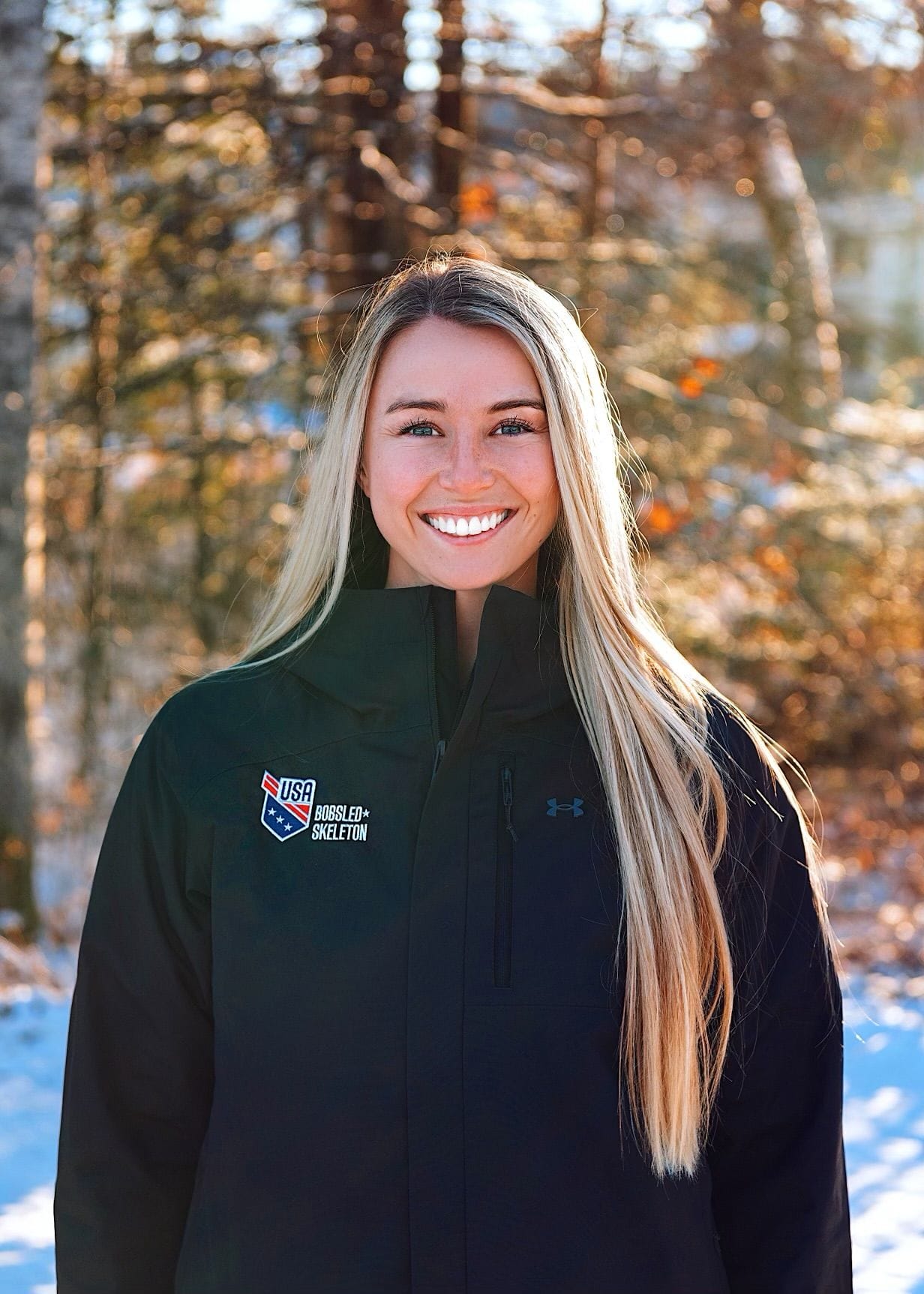 outdoor portrait of Riley smiling in her USA bobsled skeleton jacket