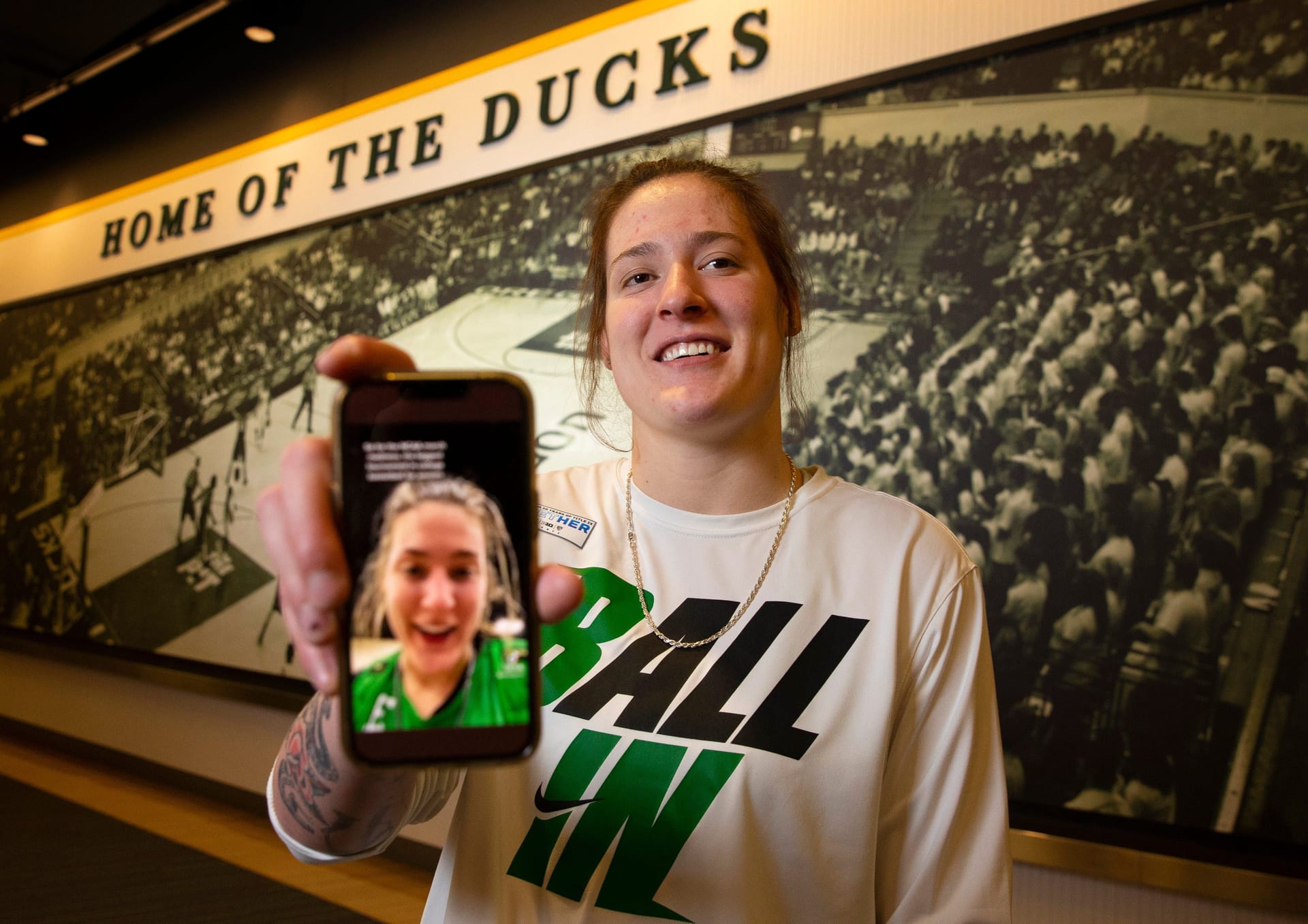 Sedona Prince holds up phone showing her social media for the Oregon Ducks