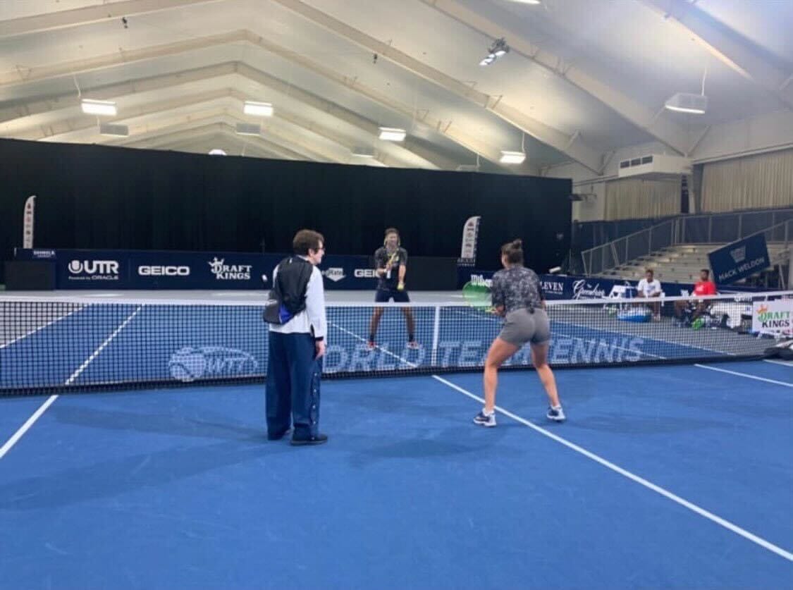 two women practice tennis at a WTT indoor facility