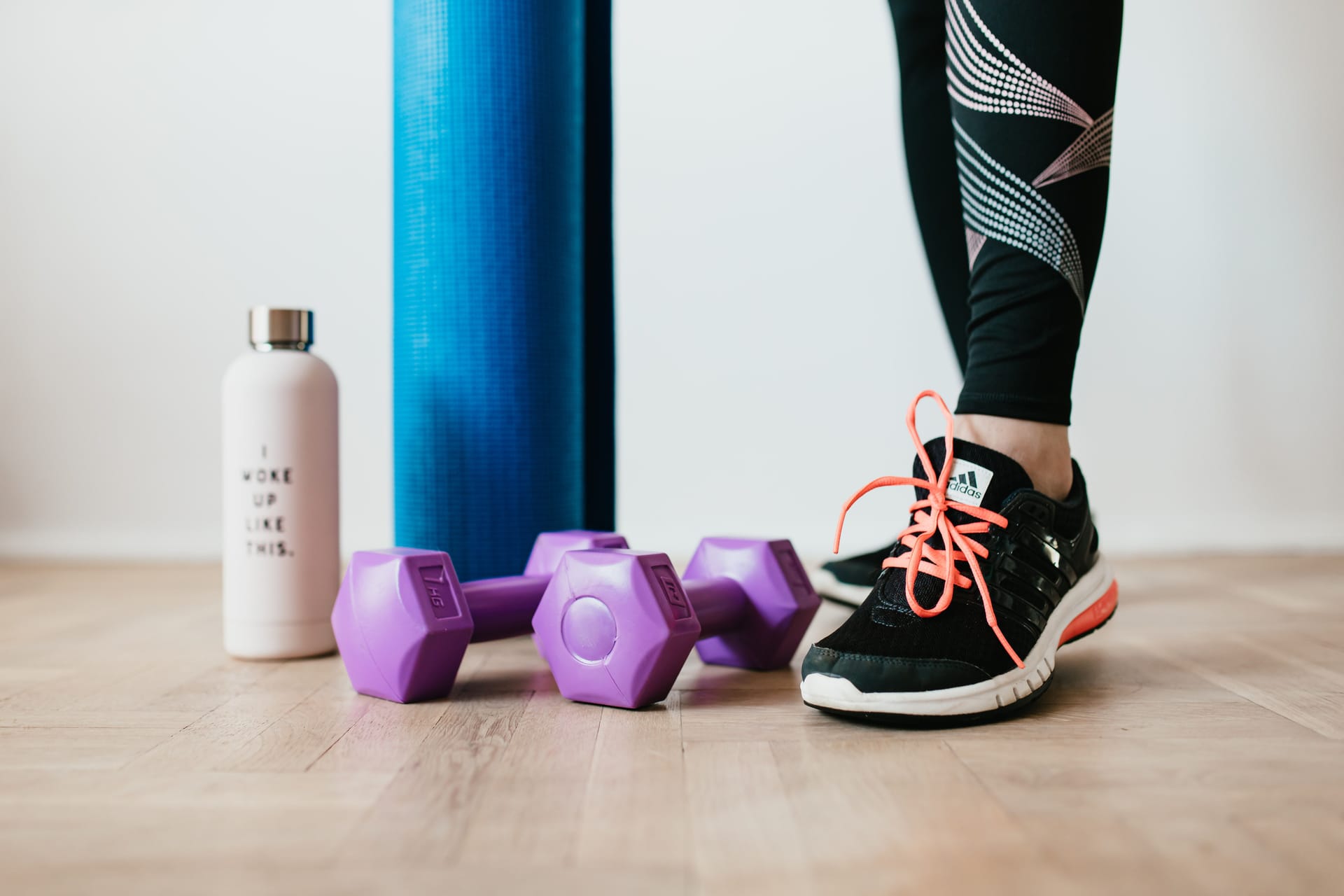 woman with sneakers, dumbells, yoga mat, and water bottle