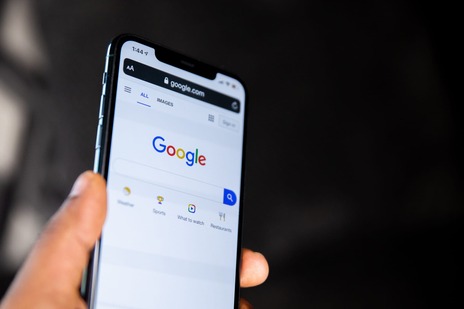 hand holding a phone displaying the Google.com search page