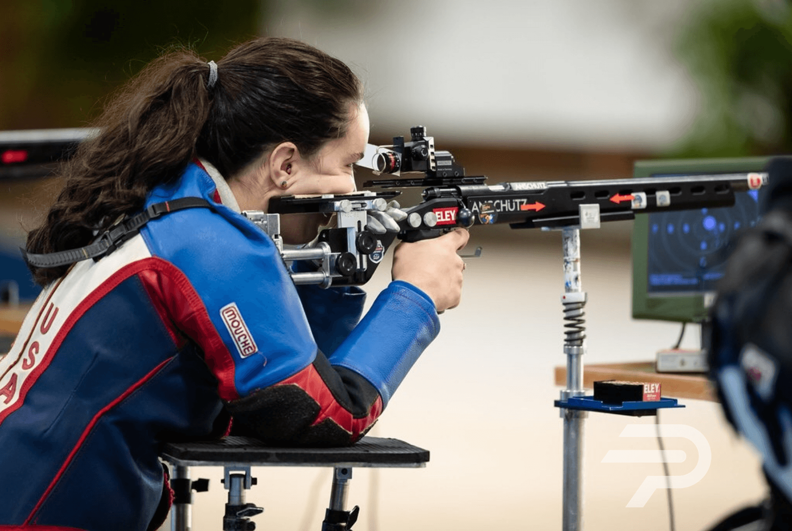 a woman aims her rifle at a Team USA shooting event