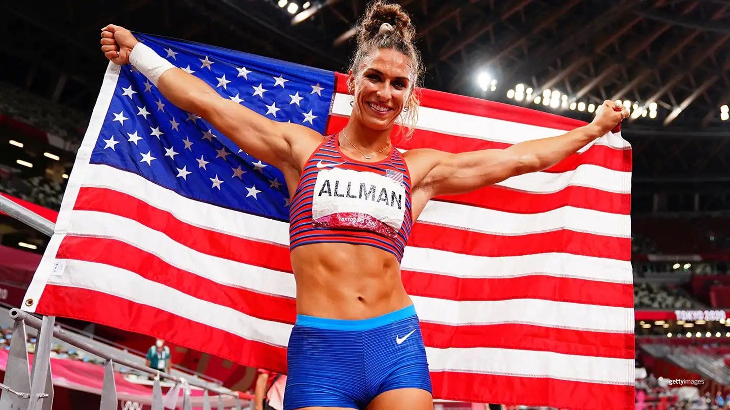 Valarie Allman holding US flag at Olympic hurdles event
