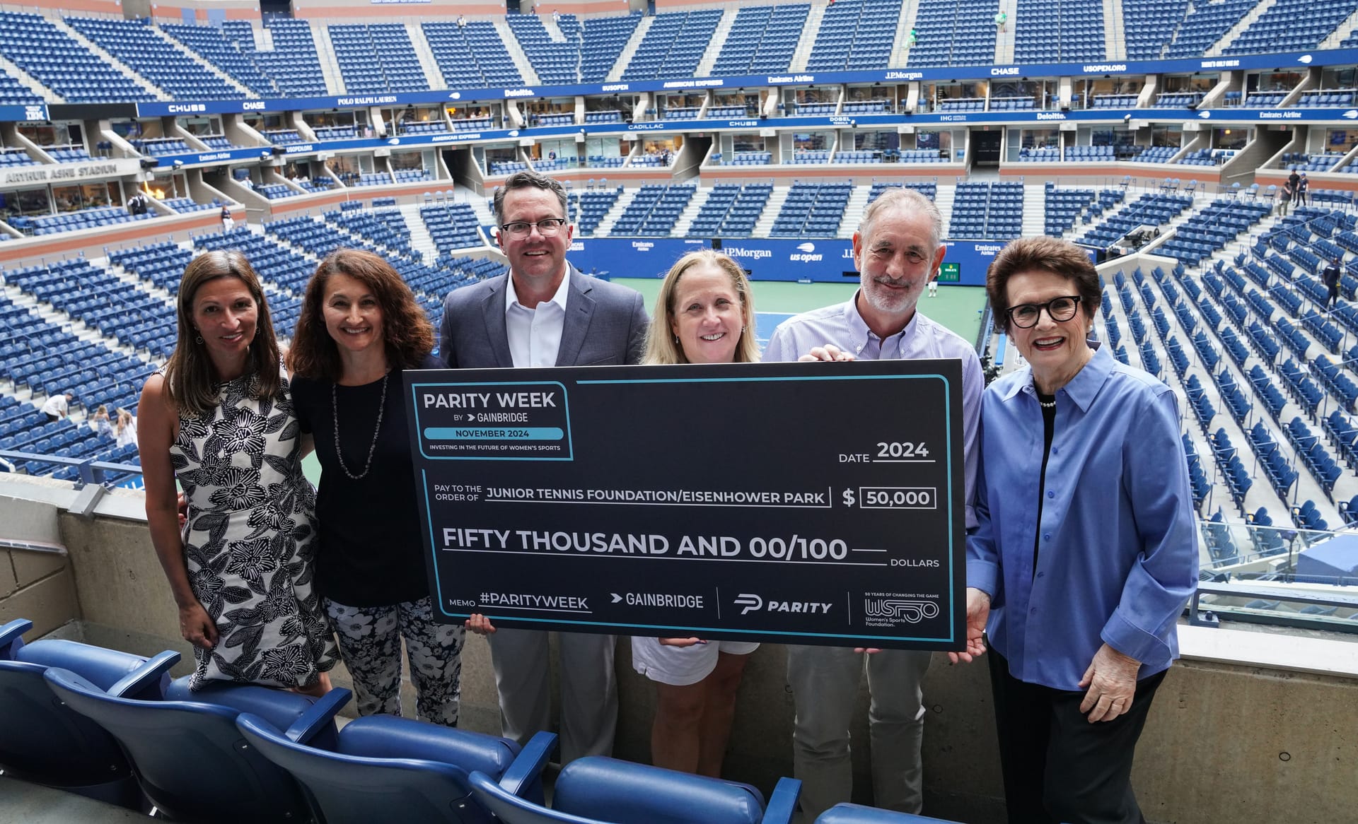 Parity CEO, Billie Jean King, and others pose with giant check for $50,000 at USTA Tennis Center