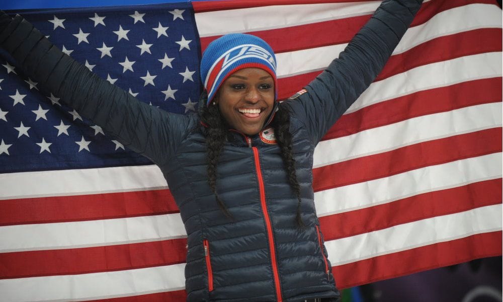 Aja Evans smiles and holds up the US flag behind her