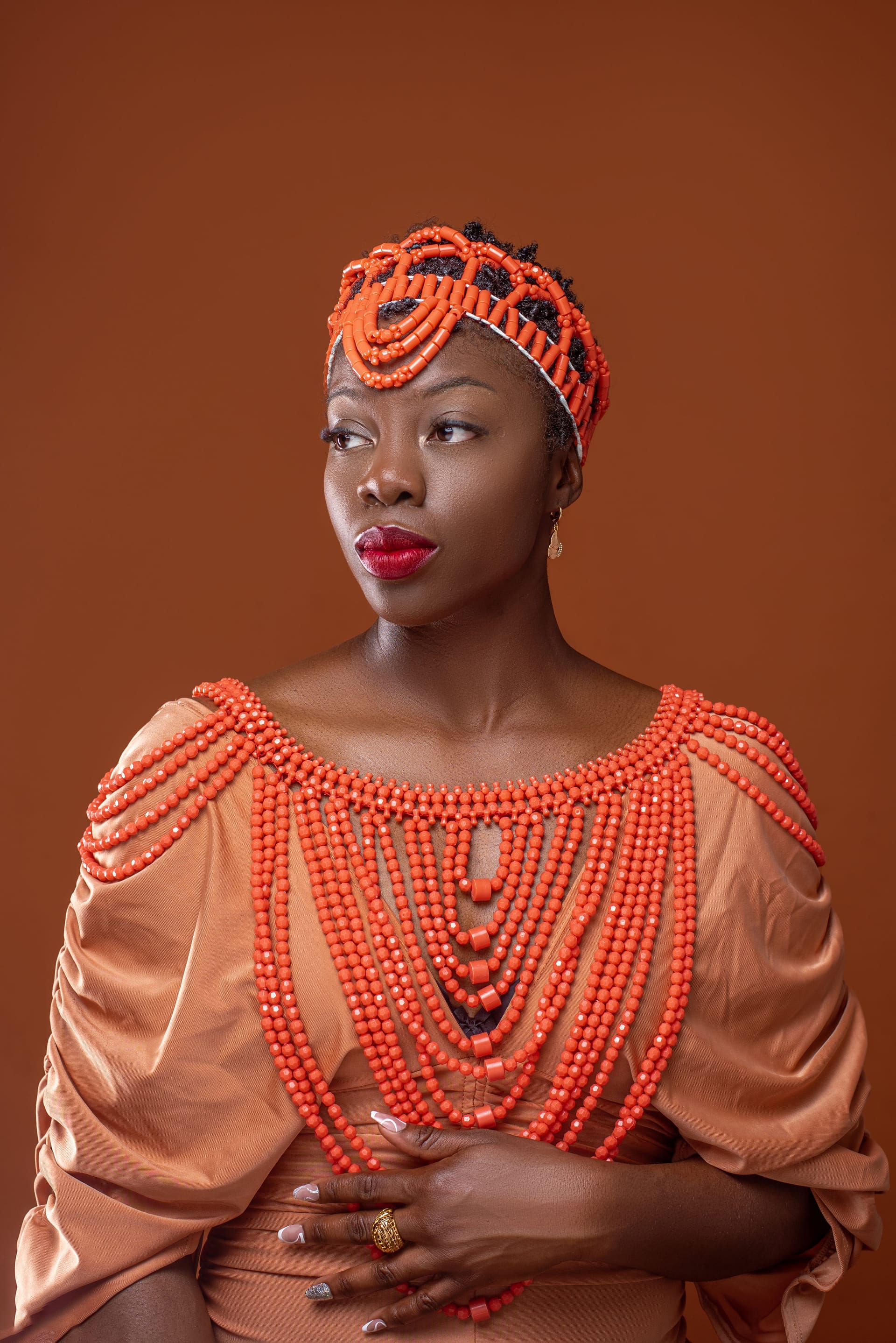 Professional portrait of Adigun in orange beaded dress and headpiece